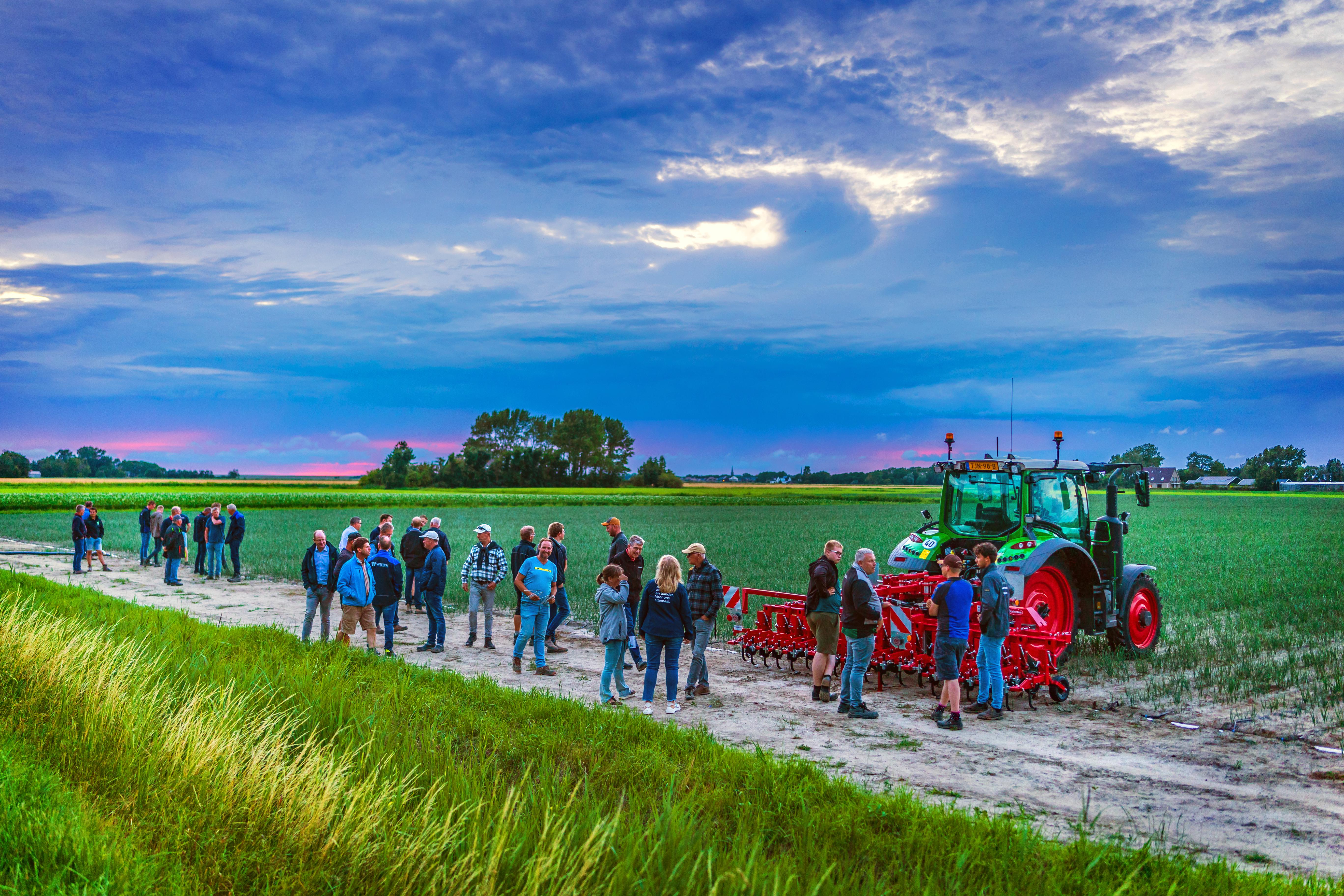 groep mensen op perceel met trekker en uien