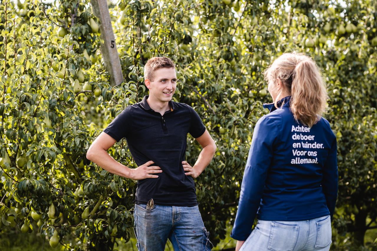 LTO Noord-medewerker in gesprek met een jonge fruitteler in de boomgaard