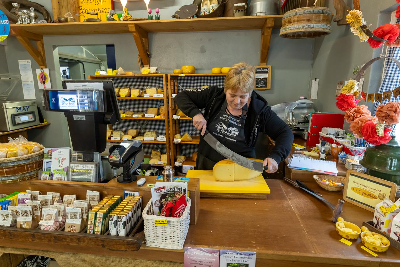Boerin snijdt kaas in een boerderijwinkel