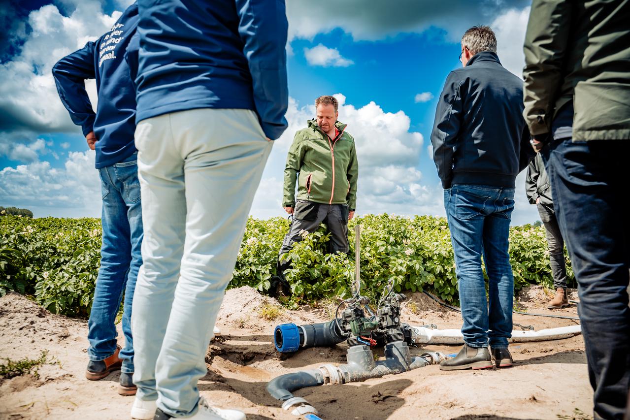 groep mensen op akkerbouwperceel met in het midden irrigatiesysteem