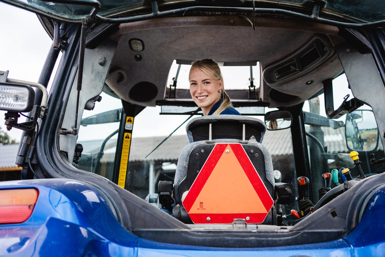 Jonge boerin op een tractor